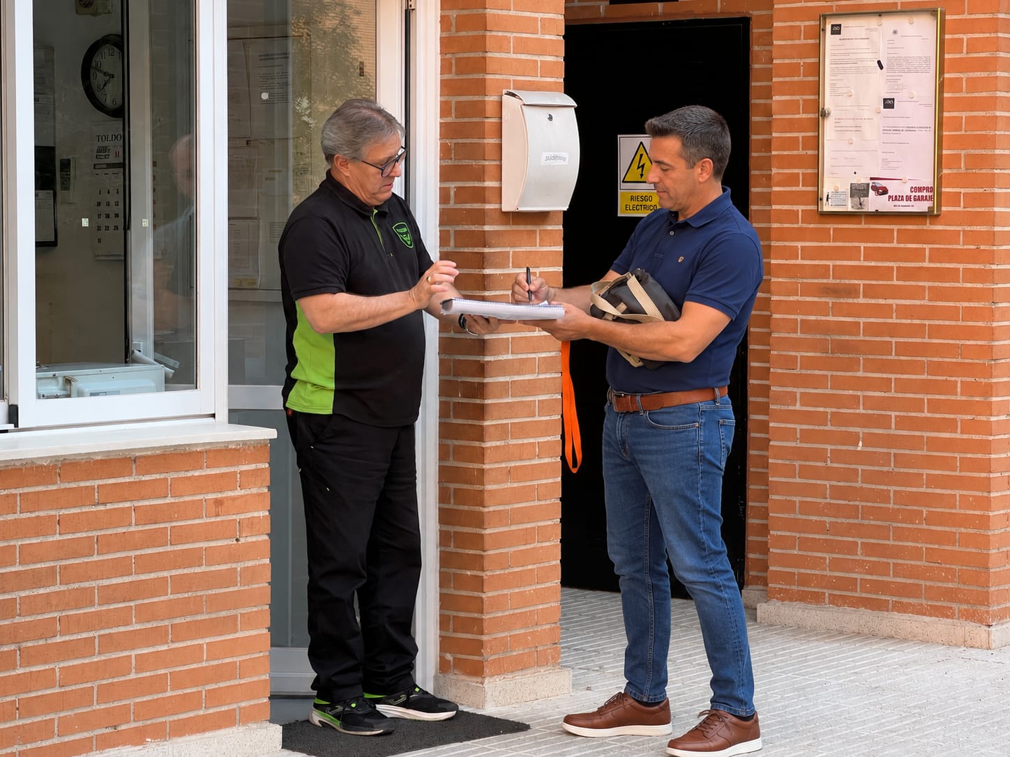Conserje de Bull Skull entregando un paquete y recogiendo la firma de un vecino en la entrada del portal